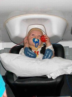 A six-month-old baby listens to sounds while a magnetoencephalograph measures the baby's brain activity